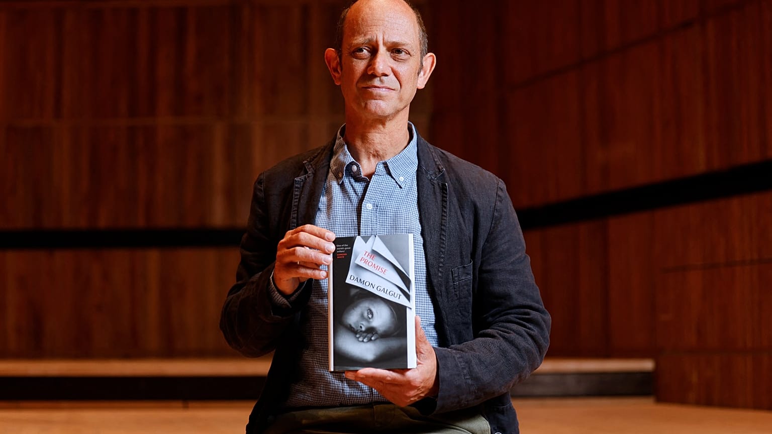 South African author Damon Galgut poses with his book 'The Promise' shortlisted for the 2021 Booker Prize for Fiction  in London on October 31, 2021.