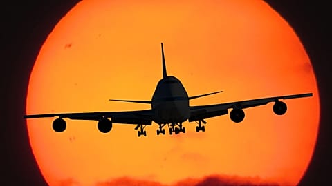 The silhouette of a jet landing with the sun behind it