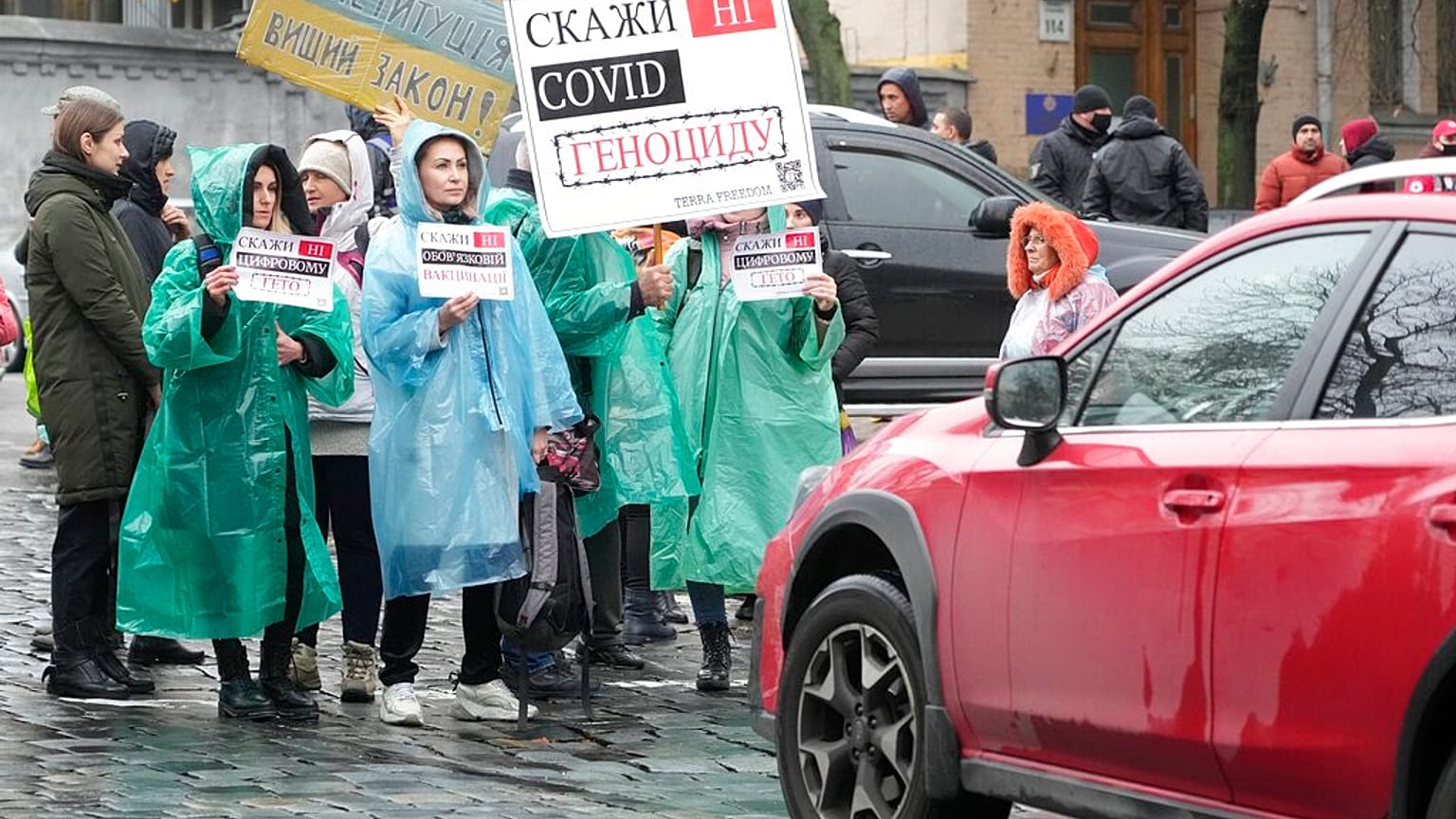 Demonstrators hold posters reading "Say No to genocide" as they try to block a street during an anti-vaccination protest in Kyiv