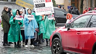 Demonstrators hold posters reading "Say No to genocide" as they try to block a street during an anti-vaccination protest in Kyiv