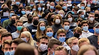 Students wear mouth-to-nose coverings while sitting close to each other during the lecture 'BWL 1' in lecture hall H1 of the Westfaelische Wilhelms-Universitaet in Muenster