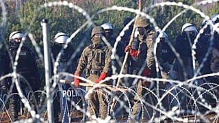 Polnische Polizisten und Grenzschutzbeamte stehen in der Nähe des Stacheldrahts Dienstag, 9. November 2021,.
