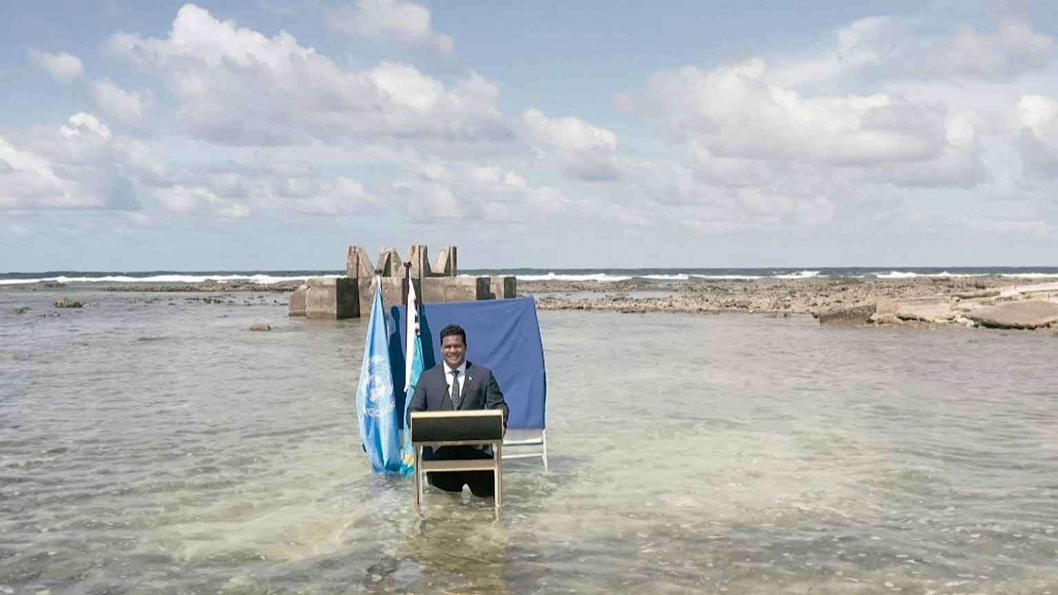Tuvalu's Foreign Minister Simon Kofe standing thigh-deep in seawater off the coast of Tuvalu as he addresses delegates at the COP26 conference in Glasgow on November 9, 2021.