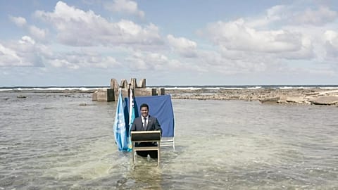 Tuvalu's Foreign Minister Simon Kofe standing thigh-deep in seawater off the coast of Tuvalu as he addresses delegates at the COP26 conference in Glasgow on November 9, 2021.