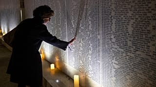 Une parent de victimes du régime nazi visite le Mur des noms après la cérémonie d'inauguration, à Vienne (Autriche) le 9 novembre 2021.
