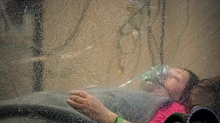 Paciente em Bucareste recebe oxigénio, isolada por cortina de plástico