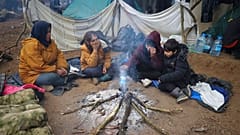 Des femmes et des enfants se réchauffant autour d'un feu à la frontière entre le Bélarus et la Pologne près de Grodno, Bélarus, 11 novembre 2021