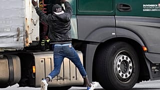 مهاجر يحاول الركوب في شاحنة من أجل عبور القناة من فرنسا إلى بريطانيا 