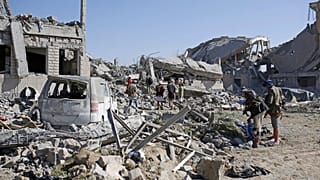 صورة من الارشيف-أشخاص يتفقدون الأنقاض في مركز احتجاز تابع للحوثيين دمرته غارات جوية بقيادة السعودية