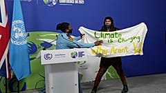 Podium in Glasgow gestürmt. Auf dem Plakat steht: "Das Klima ändert sich. Warum andern wir uns nicht?"