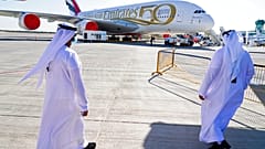 Two Emiratis walk toward an Emirates Airbus A380 jumbo jet on display at the Dubai Air Show in Dubai