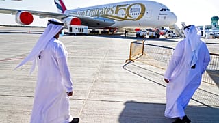 Two Emiratis walk toward an Emirates Airbus A380 jumbo jet on display at the Dubai Air Show in Dubai