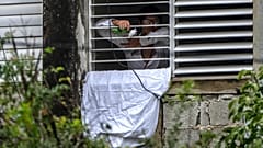 Yunior Garcia Aguilera protesta con una sábana blanca y rosas por su encierro en su vivenda
