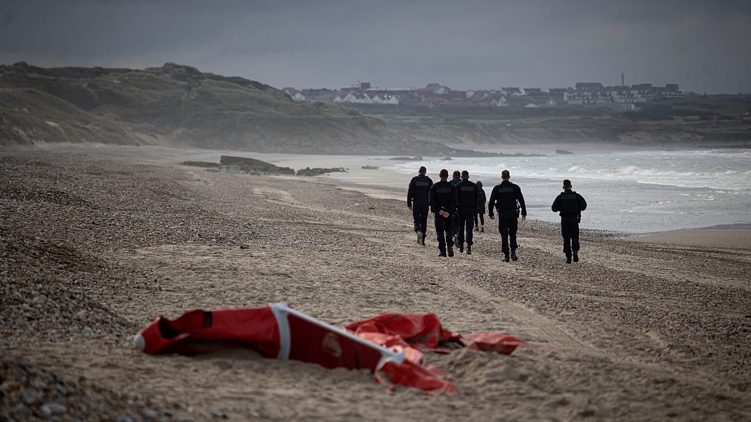 French police patrolling the beach between Ambleteusse and Wimereux, northern France, pass by the wreckage of asmall boat used by migrants, October 16, 2021.