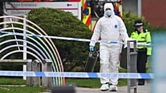 Egy védőruhába öltözött bűnügyi helyszínelő távozik a parkolóból