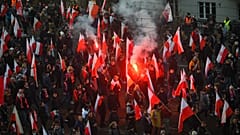 People hold Polish flags, as smoke from flares lit by members of far-right groups rises above the annual Independence Day march in Warsaw, Poland, Nov. 11, 2021.