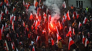 People hold Polish flags, as smoke from flares lit by members of far-right groups rises above the annual Independence Day march in Warsaw, Poland, Nov. 11, 2021.