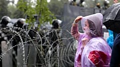 A woman stands at a barbed wire fence in front of a police line toward President Lukashenko's Independence Palace in Minsk, September 2020