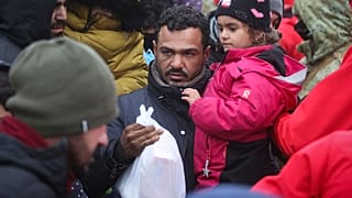 رجل يحمل طفلته على الحدود بين بيلاروس وبولندا بالقرب من غرودنو ، بيلاروسيا