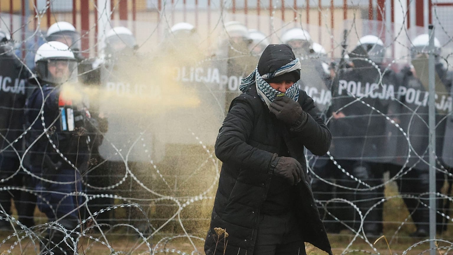 Polish serviceman sprays tear gas during clashes between migrants and Polish border guards at the Belarus-Poland border near Grodno, Belarus, on Tuesday, Nov. 16, 2021