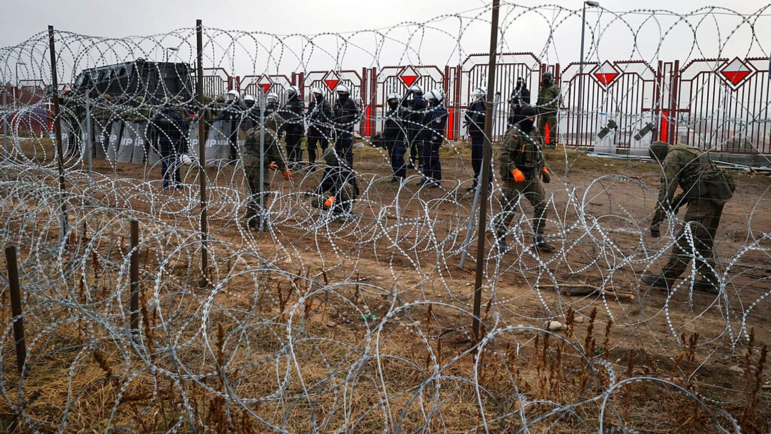 Militari polacchi dall'altra parte della recinzione di filo spinato al checkpoint di Kuznica, al confine tra Bielorussia e Polonia
