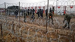 Militari polacchi dall'altra parte della recinzione di filo spinato al checkpoint di Kuznica, al confine tra Bielorussia e Polonia