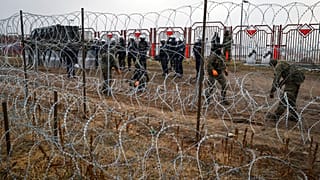 Militari polacchi dall'altra parte della recinzione di filo spinato al checkpoint di Kuznica, al confine tra Bielorussia e Polonia