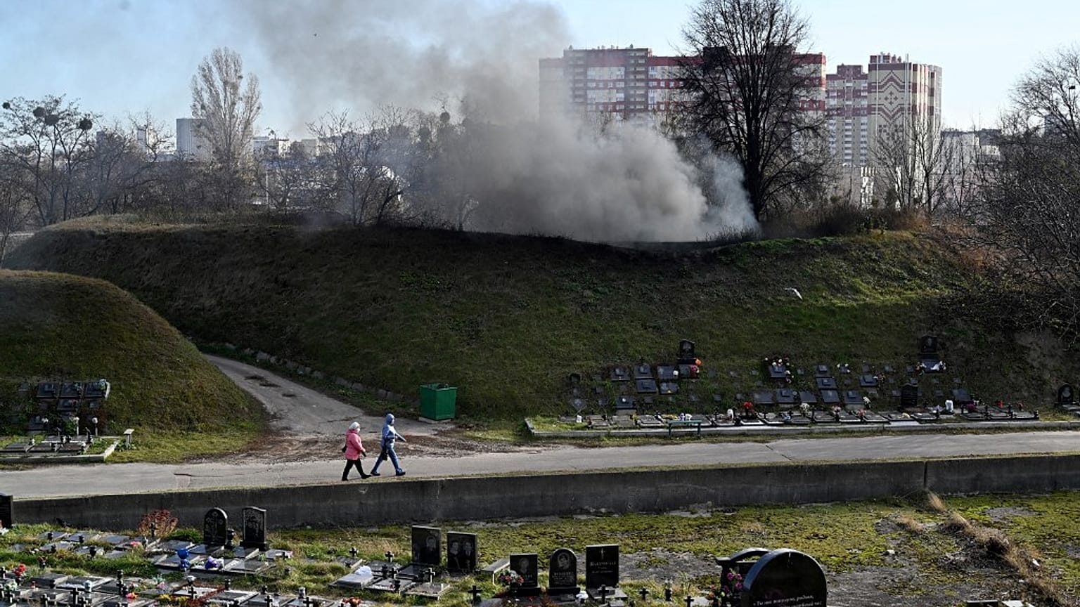 Women walk past a fuming chimney of a crematorium at a cemetery in Kiev on November 11, 2021, amid the ongoing COVID-19 pandemic.