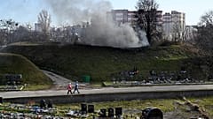 Women walk past a fuming chimney of a crematorium at a cemetery in Kiev on November 11, 2021, amid the ongoing COVID-19 pandemic.