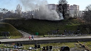 Women walk past a fuming chimney of a crematorium at a cemetery in Kiev on November 11, 2021, amid the ongoing COVID-19 pandemic.