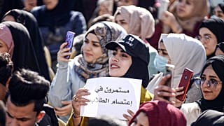 طالبة عراقية ترفع لافتة "مستمرون في اعتصام الطلاب" في احتجاجات مناهضة للحكومة خارج جامعة الكوفة، العراق، 22 ديسمبر 2019