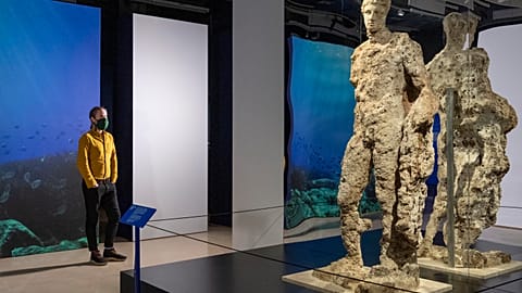 Visitor observes Hermes statue at new exhibition