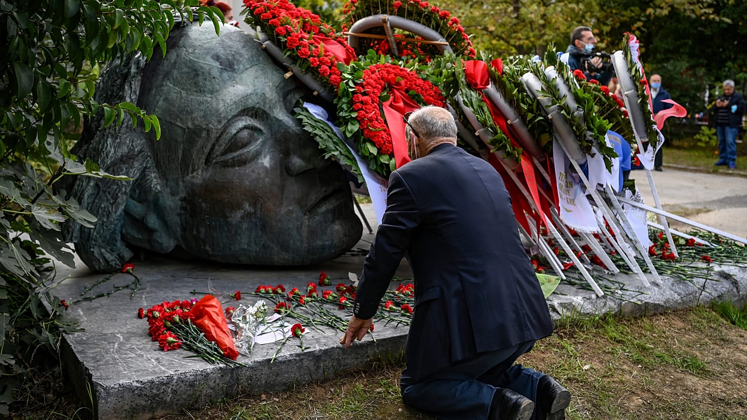 Ein Mann kniet in Athen an einem Mahnmal nieder