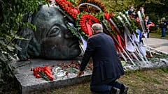 Ein Mann kniet in Athen an einem Mahnmal nieder