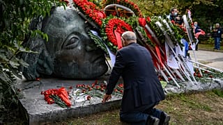 Ein Mann kniet in Athen an einem Mahnmal nieder
