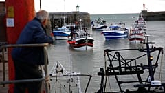 A man watches trawlers arriving in the port of Granville, Normandy, Thursday, Nov. 4, 2021.