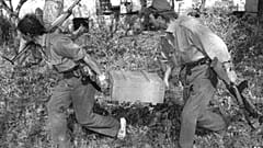 Dos soldados territoriales serbios corren con una caja de granadas capturada en las afueras de la ciudad de Vukovar, Croacia, el viernes 27 de septiembre de 1991