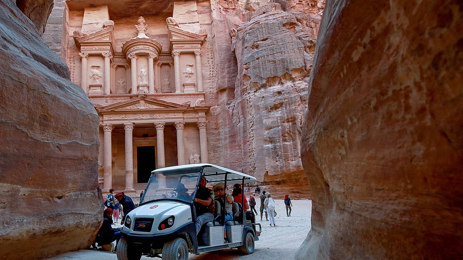 Tourists ride an electric cart, during their trip to Jordan's famed ancient city of Petra, on October 27, 2021. 