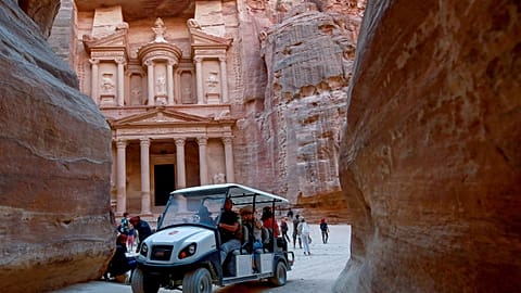 Tourists ride an electric cart, during their trip to Jordan's famed ancient city of Petra, on October 27, 2021. 