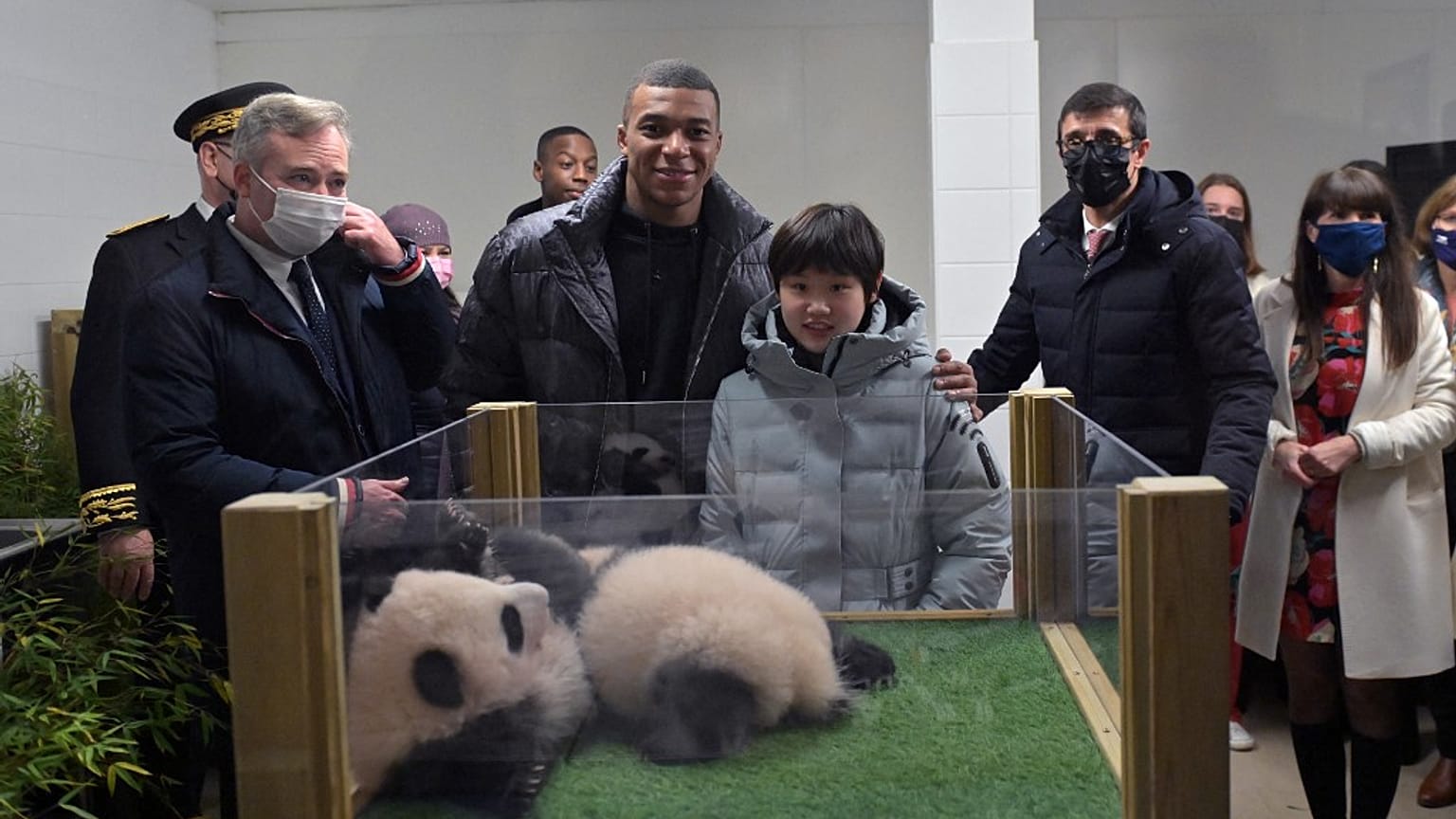 La championne olympique chinoise Zhang Jiaqi (à droite) et le footballeur français Kylian Mbappé (à gauche) posent avec les deux pandas lors de la cérémonie du nom, 18/11/2021