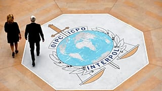 In this photo taken on Thursday, Nov.8, 2018 people walk on the Interpol logo at the international police agency headquarters in Lyon, central France