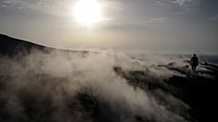 A tourist walks in the fumaroles of a crater on the volcanic island of Vulcano.