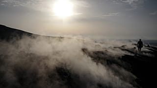 A tourist walks in the fumaroles of a crater on the volcanic island of Vulcano.