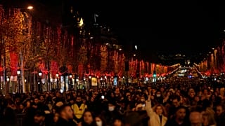 Spectators gather to attend the Champs Elysee Avenue illumination ceremony for the Christmas season, in Paris, Sunday, Nov. 21, 2021.