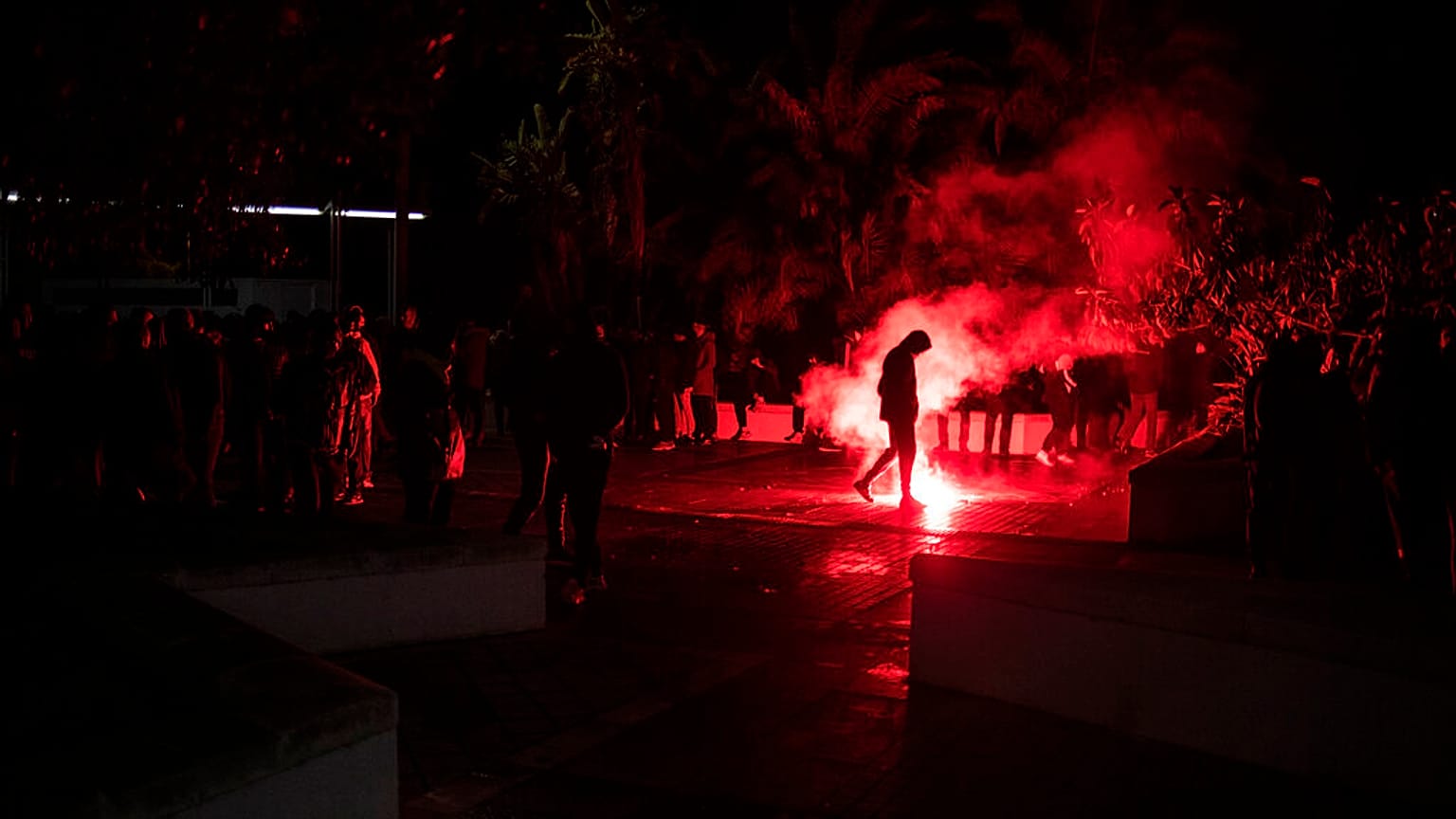 Un huelguista camina junto a una bengala durante la noche en Cádiz.