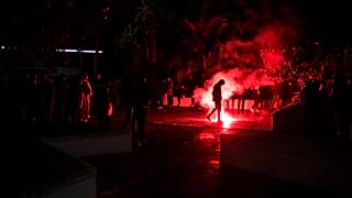 Un huelguista camina junto a una bengala durante la noche en Cádiz.