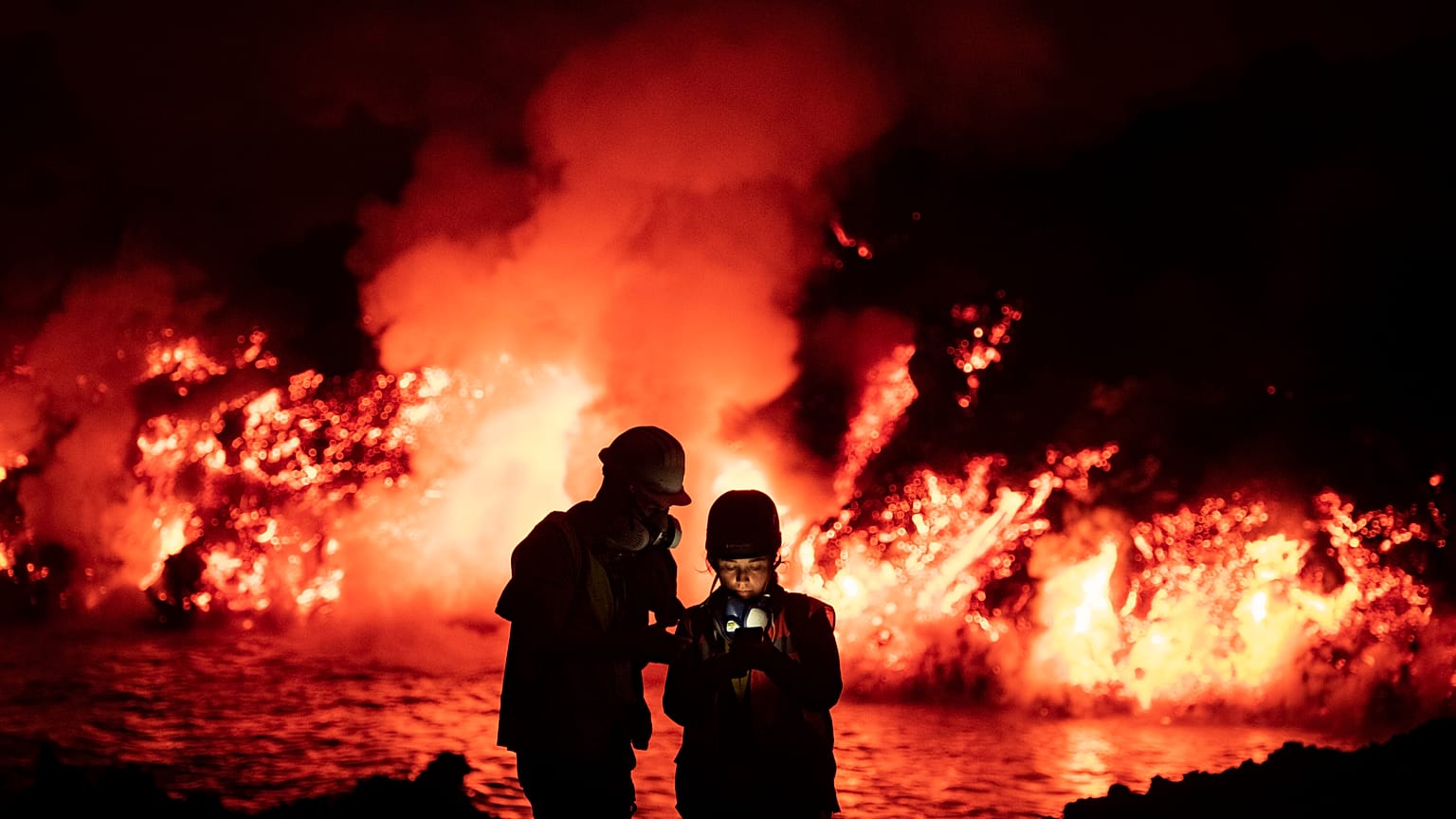 Scientists take geophysics measurements as lava flows from a volcano reaching the sea on the Canary island of La Palma, Spain, Thursday, Nov. 11, 2021