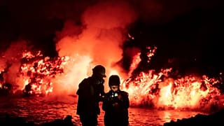 Scientists take geophysics measurements as lava flows from a volcano reaching the sea on the Canary island of La Palma, Spain, Thursday, Nov. 11, 2021
