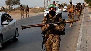 مسلحون من كتائب عز الدين القسام، الجناح العسكري لحركة حماس، يسيرون ببنادقهم على طول الطريق الرئيسي لمخيم النصيرات وسط قطاع غزة، الخميس 28 تشرين الأول (أكتوبر) 2021