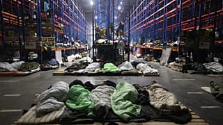 Migrants sleep at a logistics centre at the checkpoint "Kuznitsa" at the Belarus-Poland border near Grodno, Belarus, Monday, Nov. 22, 2021.